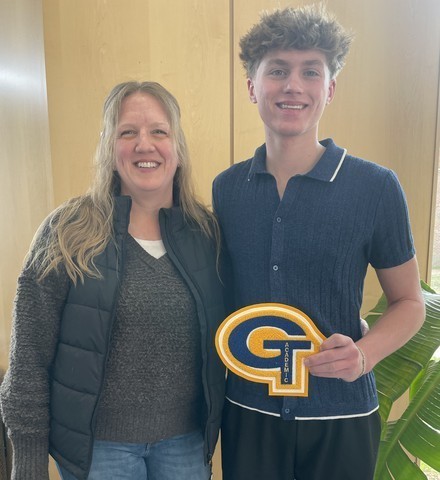 A student holds up his academic letter joined by family following the ceremony.