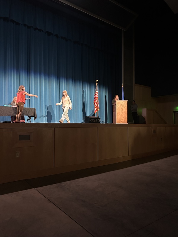 Spring 2026 Academic Awards Ceremony. A student crosses the stage to receive an award from school administrators after their name is announced by Student Services staff.