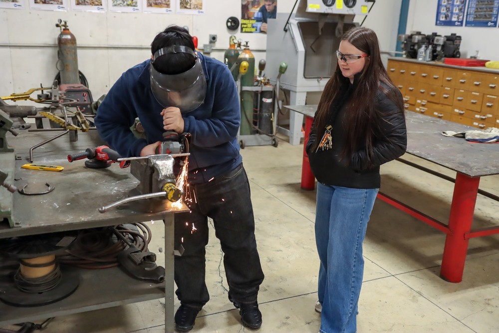 teacher helping welding student