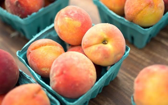 peaches in green cardboard baskets