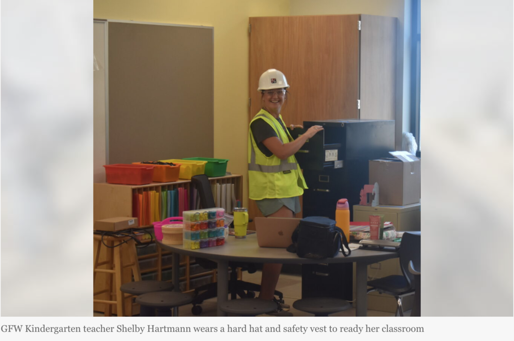 GFW kindergarten teacher Shelby Hartmann wears a hard hat and safety vest to ready her classroom