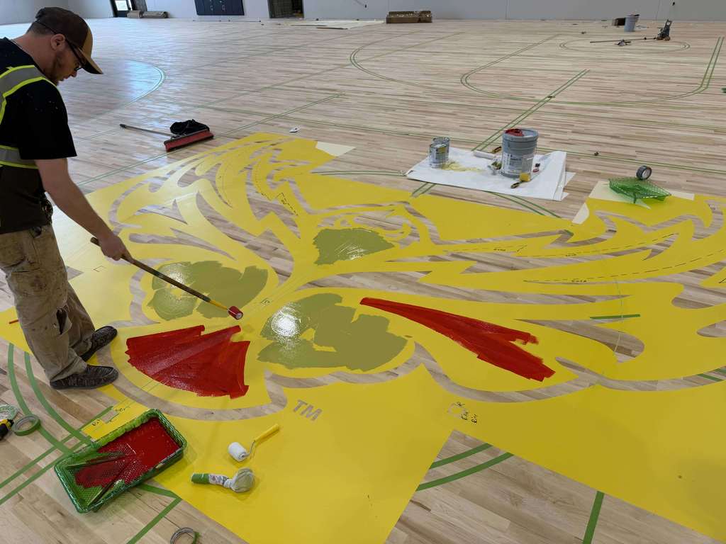 man painting gym floor