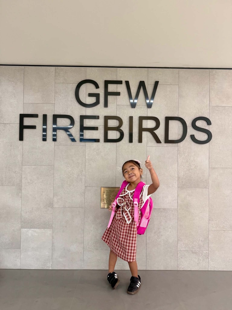 Girl with thumbs up in front of GFW Firebirds sign