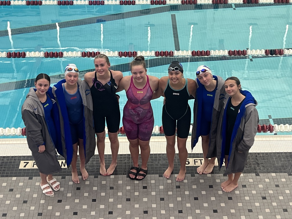 Girls swim team members posing near pool