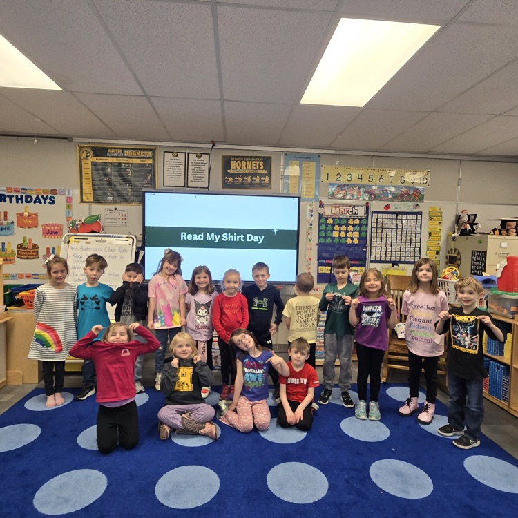 a group of students smiling for a photo showing their shirts for read my shirt spirit day