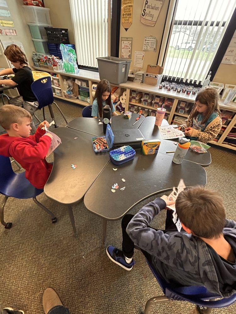 Elementary students sitting at desks creating and getting ready to plant grass as they begin their new unit on living things.