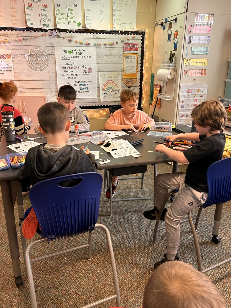 Elementary students sitting at desks creating and getting ready to plant grass as they begin their new unit on living things.
