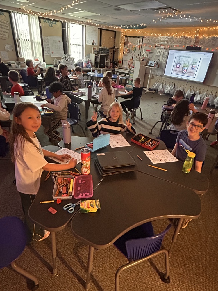 Elementary students sitting at desks creating and getting ready to plant grass as they begin their new unit on living things.