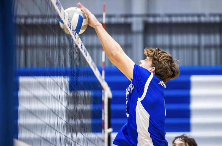 CHS Boys Club Volleyball team, one player blocking at the net
