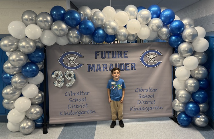 kindergarten student in front of kindergarten banner