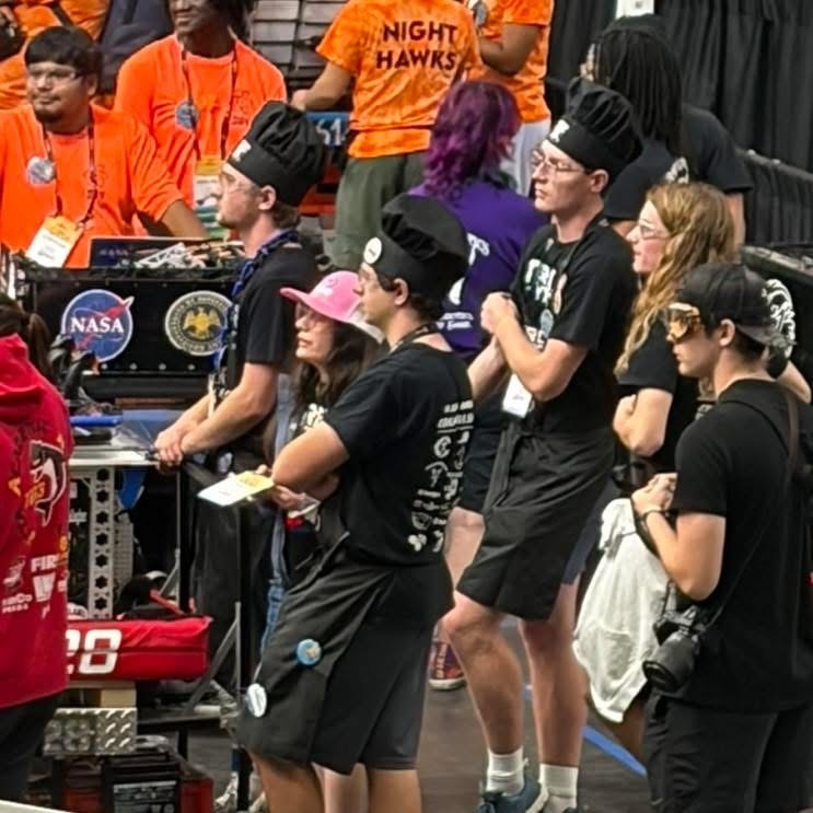 7 team 6528 team members standing while watching the robotics match