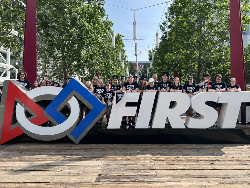 team photo of team 6528 standing in front of a large First sign