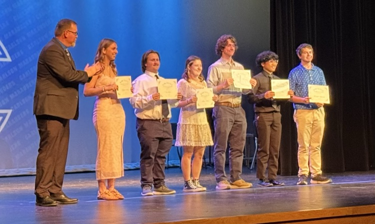 students receiving scholarships on a stage