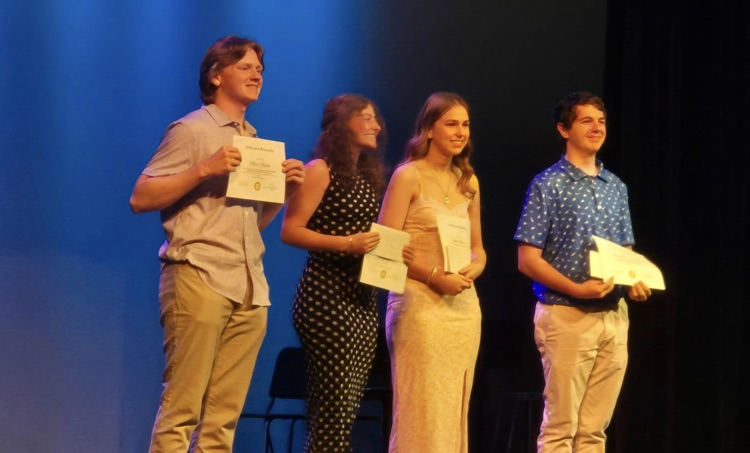 students receiving scholarships on a stage