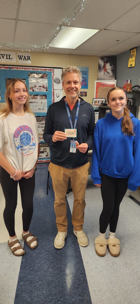 Two students stand with a teacher in the middle and smiling for the camera