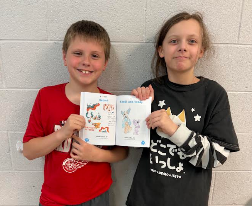 Elementary students Nolan and Taylor hold a book displaying their artwork.