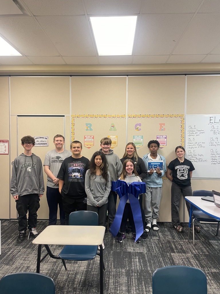 Mrs. Wylie's Advisory class posing for a picture holding a bow while standing against the wall