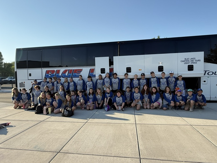 fifth grade students standing in front of the charter bus that is about to take them to fifth grade camp