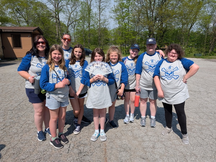a group of fifth grade students and chaperones smiling for a picture at camp after just arriving 