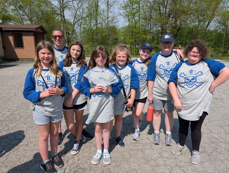 a group of fifth grade students and chaperones smiling for a picture at camp after just arriving 