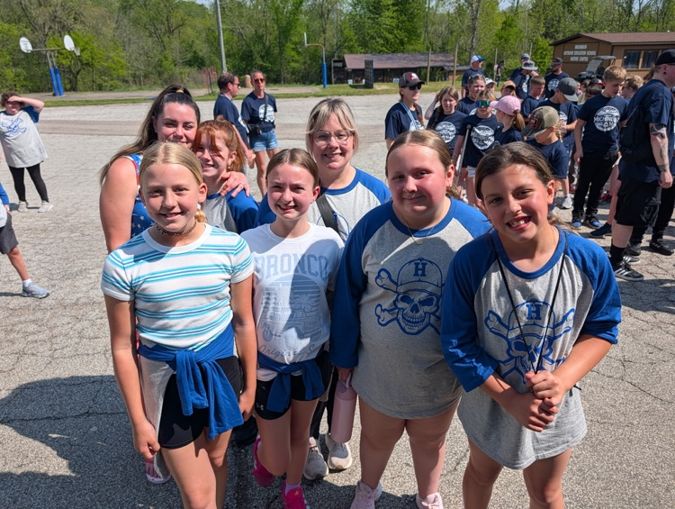 a group of fifth grade students and chaperones smiling for a picture at camp after just arriving 