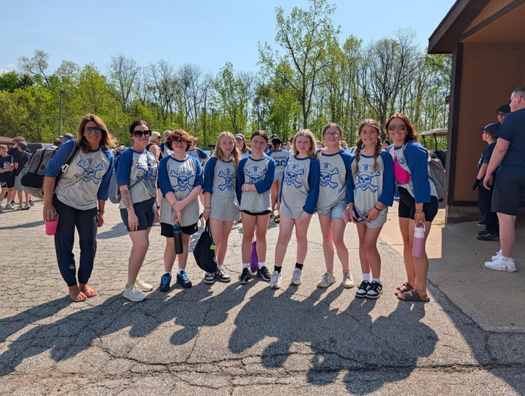 a group of fifth grade students and chaperones smiling for a picture at camp after just arriving 