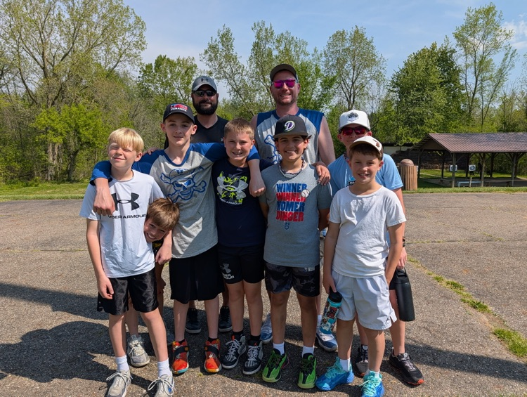 a group of fifth grade students and chaperones smiling for a picture at camp after just arriving 