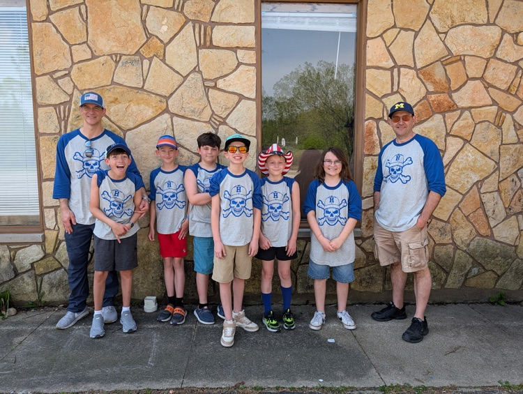 a group of fifth grade students and chaperones smiling for a picture at camp after just arriving 