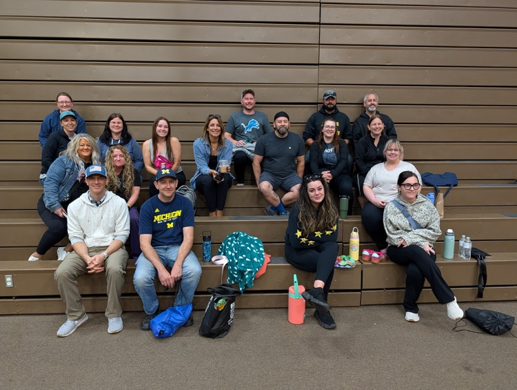 group photo of all the parent chaperones at fifth grade camp sitting on bleachers smiling for a photo