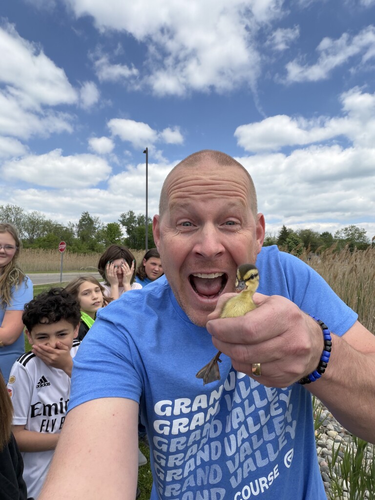Mr. Bouwman is holding a baby duck and students are behind him watching.