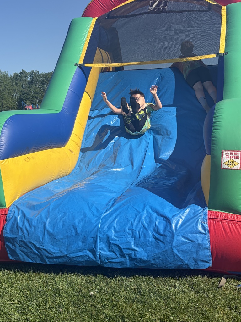 Student going down the obstacle course slide at field day.