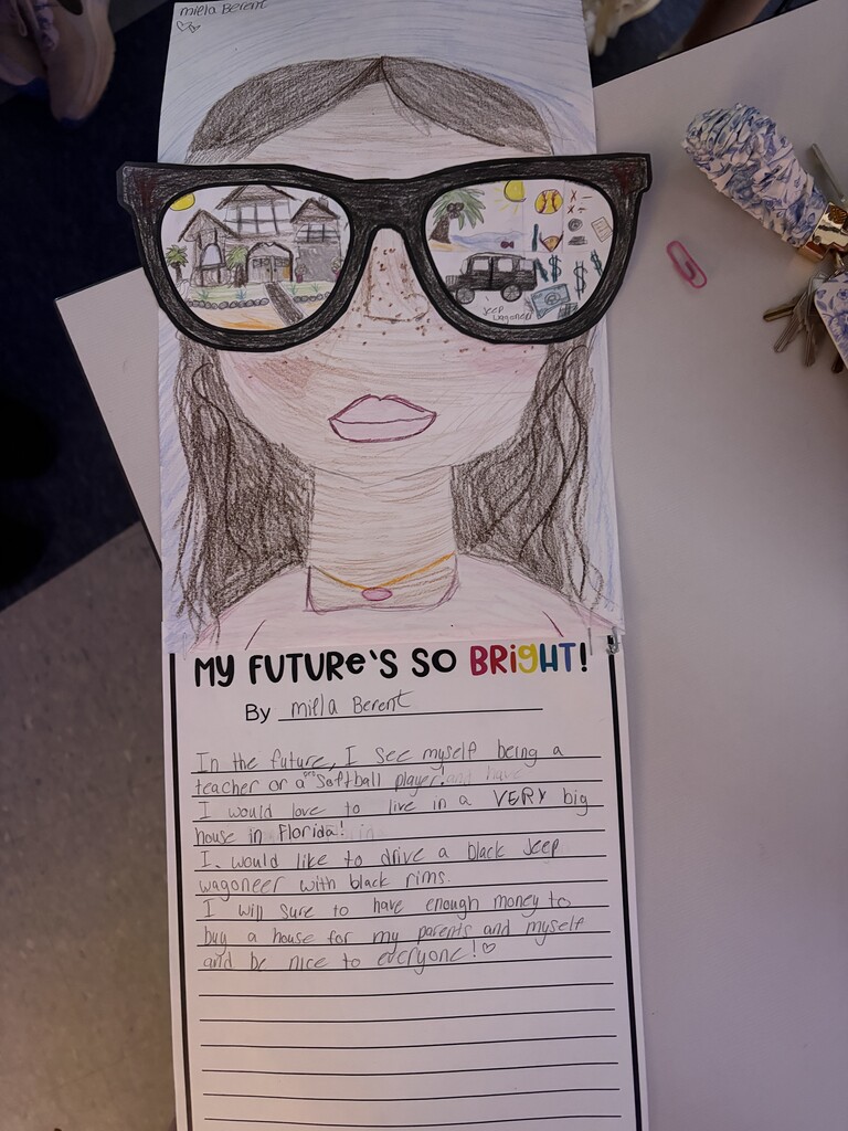 A paper assignment with picture of a girl with glasses is laying on a desk with writing below the girl