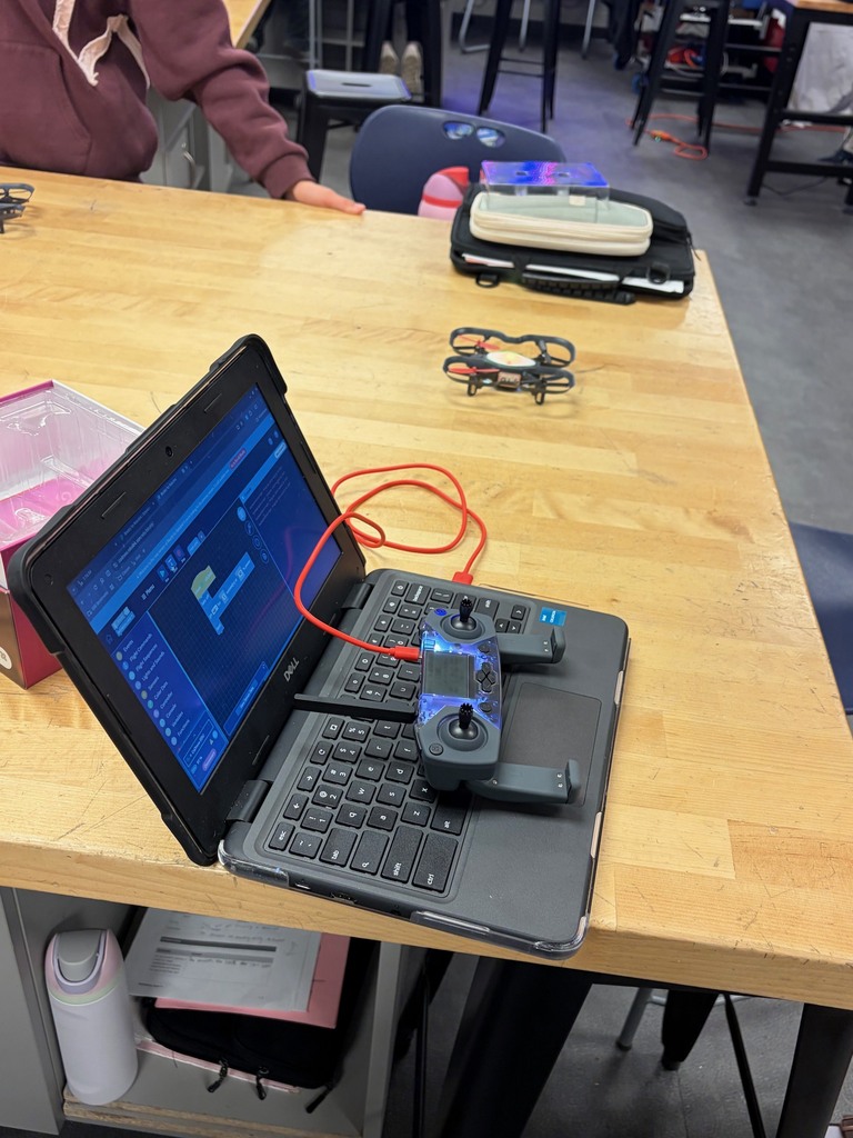 There is a Chromebook with a drone on it on a table