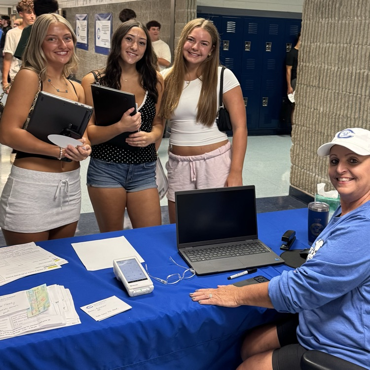students and staff standing at a table