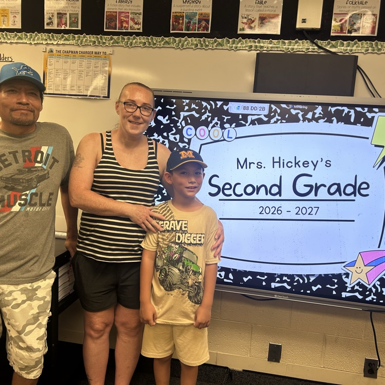 parents and student posing next to board that says welcome to open house in 2nd grade 