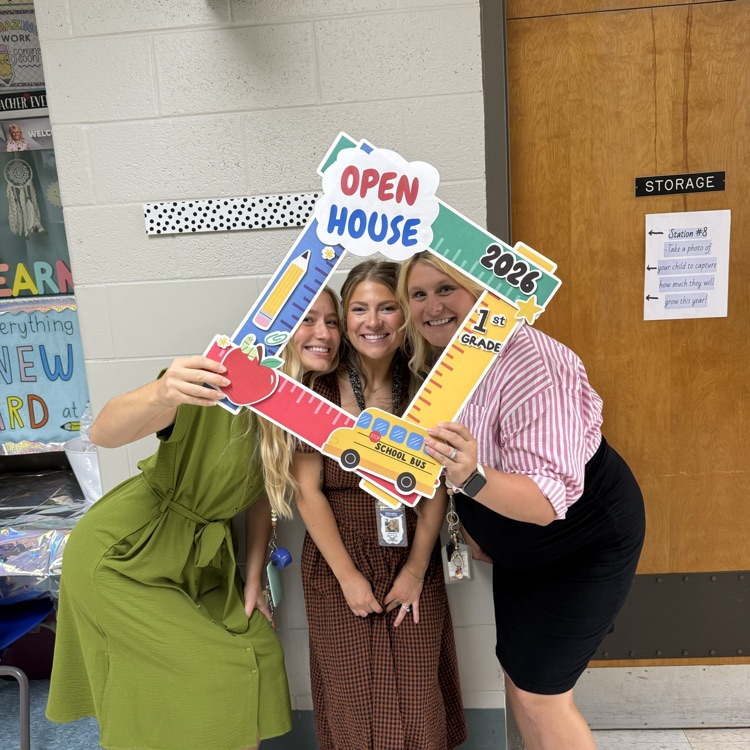 3 teachers smiling with open house sign in school hallway 
