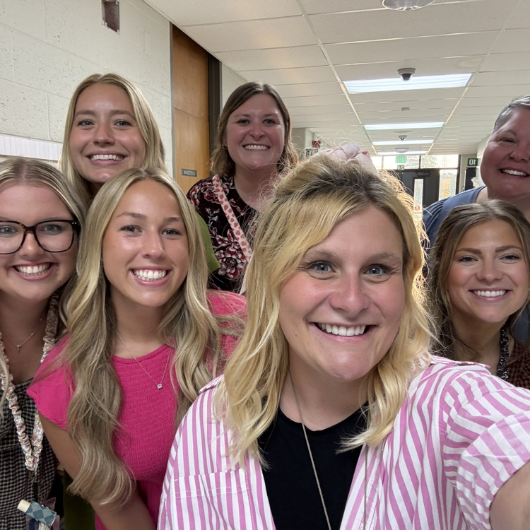 teachers smiling in group photo in hallway