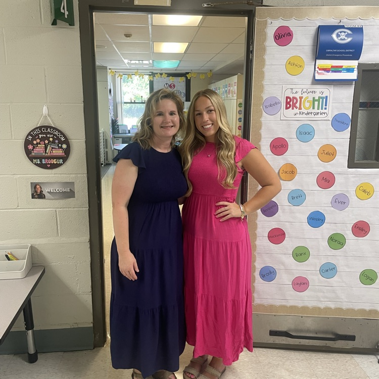 two teachers smiling for photo in front of kindergarten doorway 