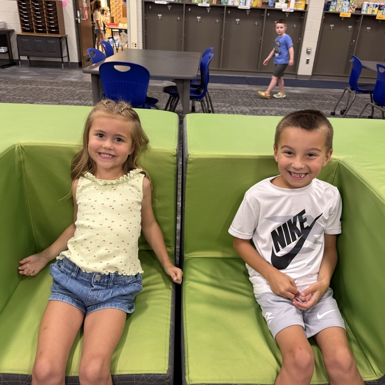 two students sitting in chairs in the media center