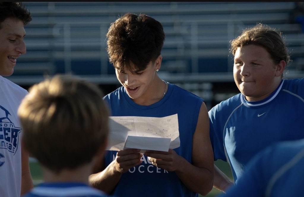 Four soccr plays are huddled together and taking direction from a student coach
