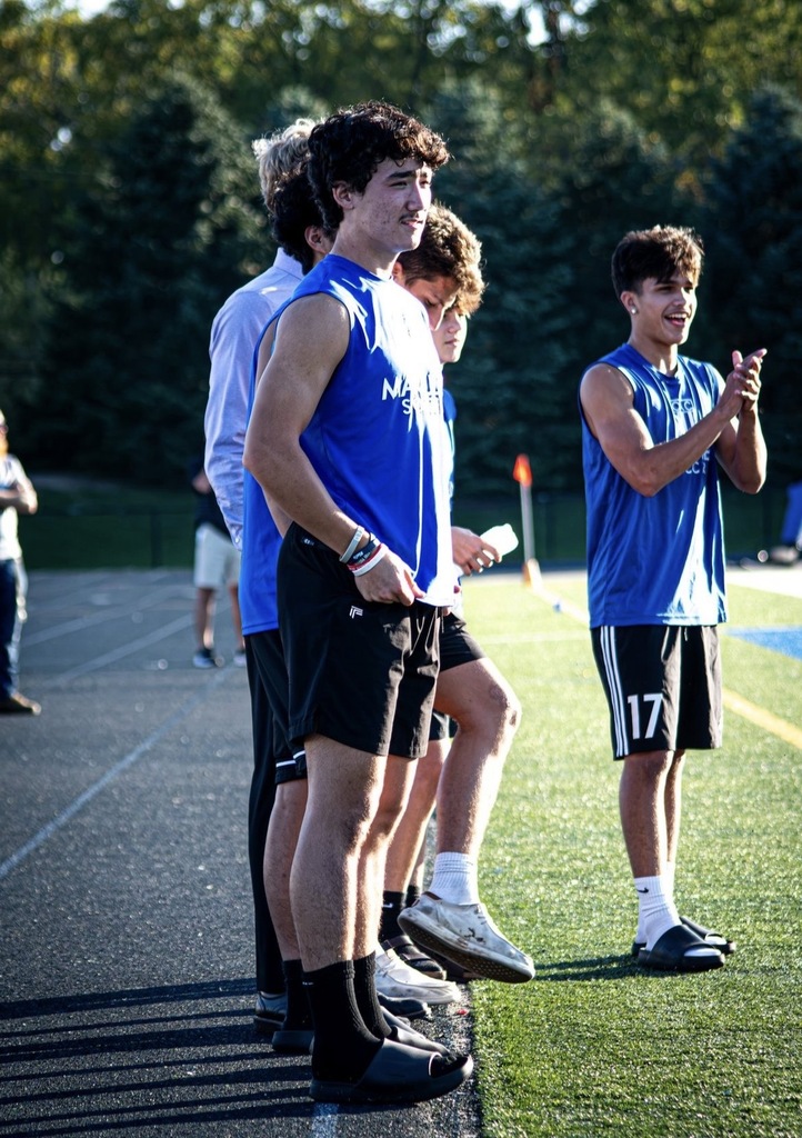 A group of boys are on the sideline at a soccer game and cheering on the team