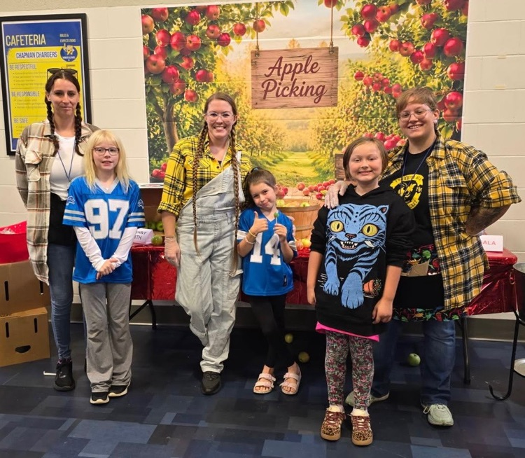 Kitchen staff and students pose by a fun apple-picking display in the cafeteria to celebrate Michigan Apple Crunch Day.