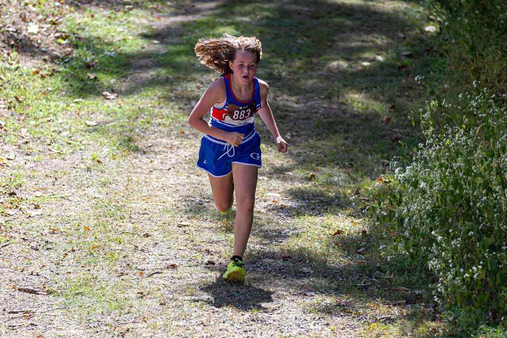 student running down gravel hill, forested area