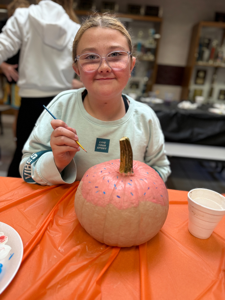 student painting a pumpkin to look like a donut