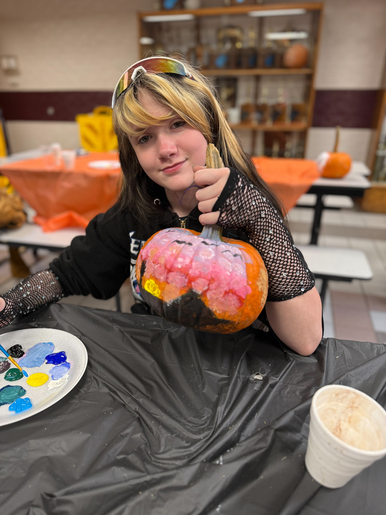 student holding up her pumpkin with a landscape scene on it