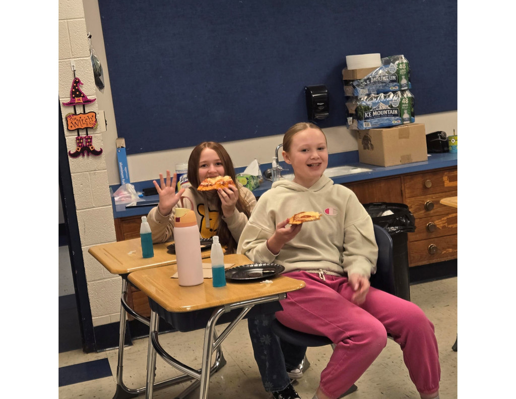 students waving while eating pizza