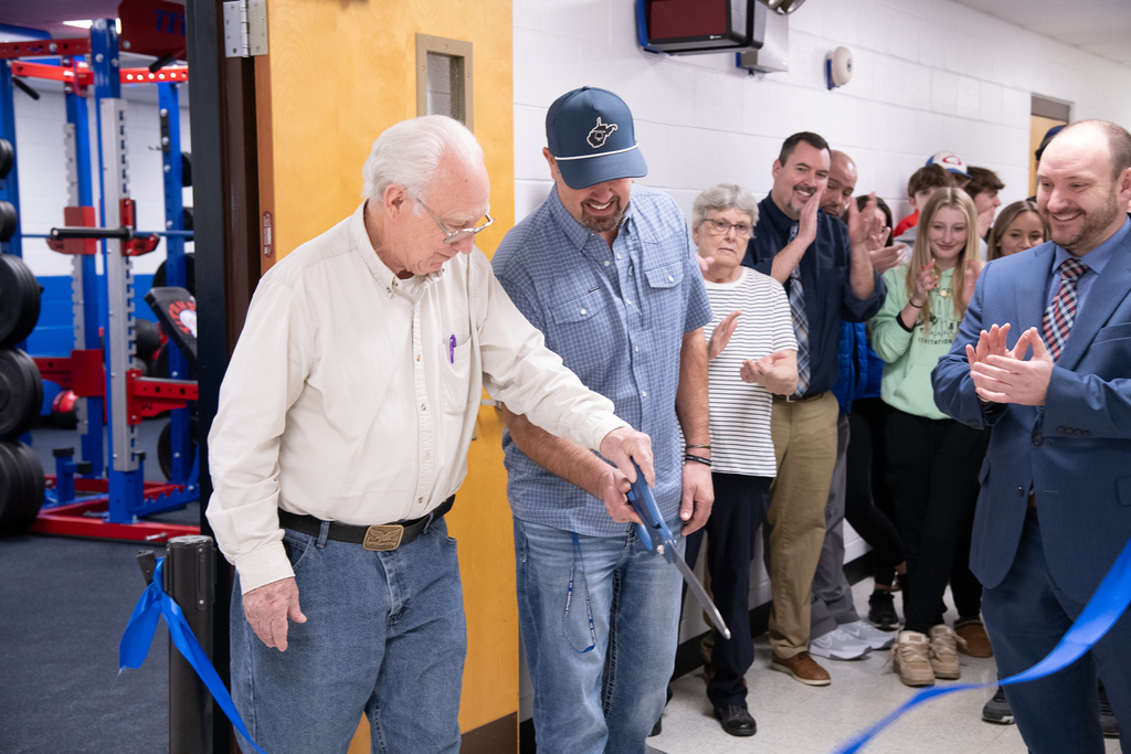A group of people watches on as L. Barton and B. Chapman cut the ribbon 