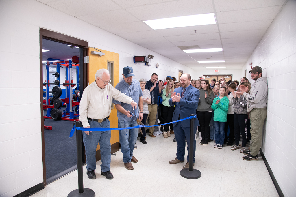 A group of people watches on as L. Barton and B. Chapman cut the ribbon 