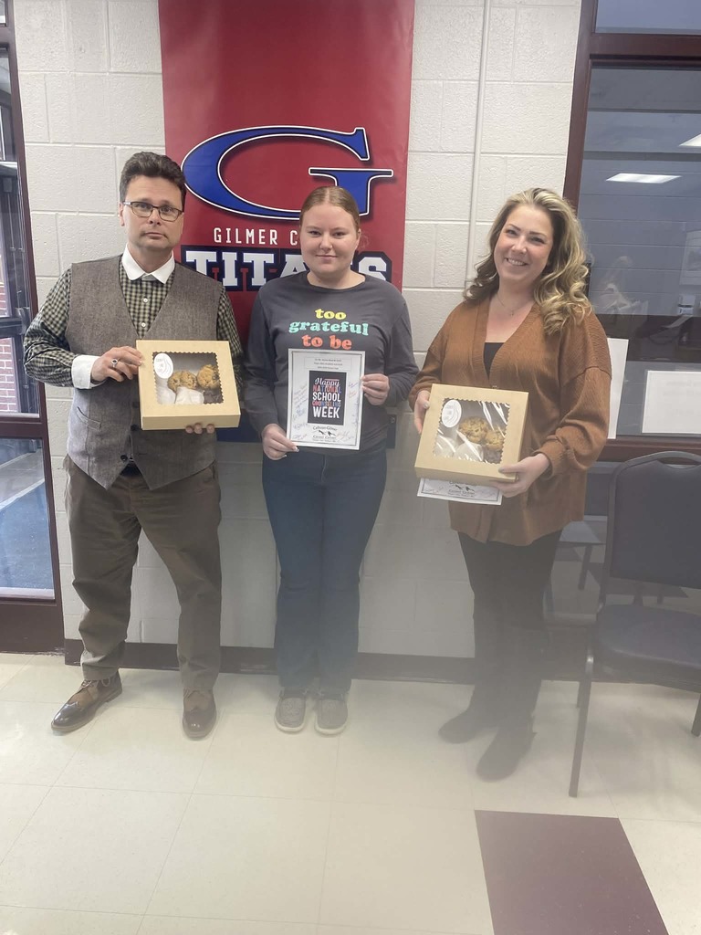 mr reed, Mrs fox, and a student with the treat boxes pose in the main office
