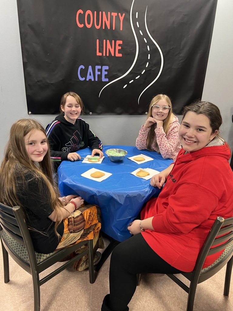 four students decorating cookies